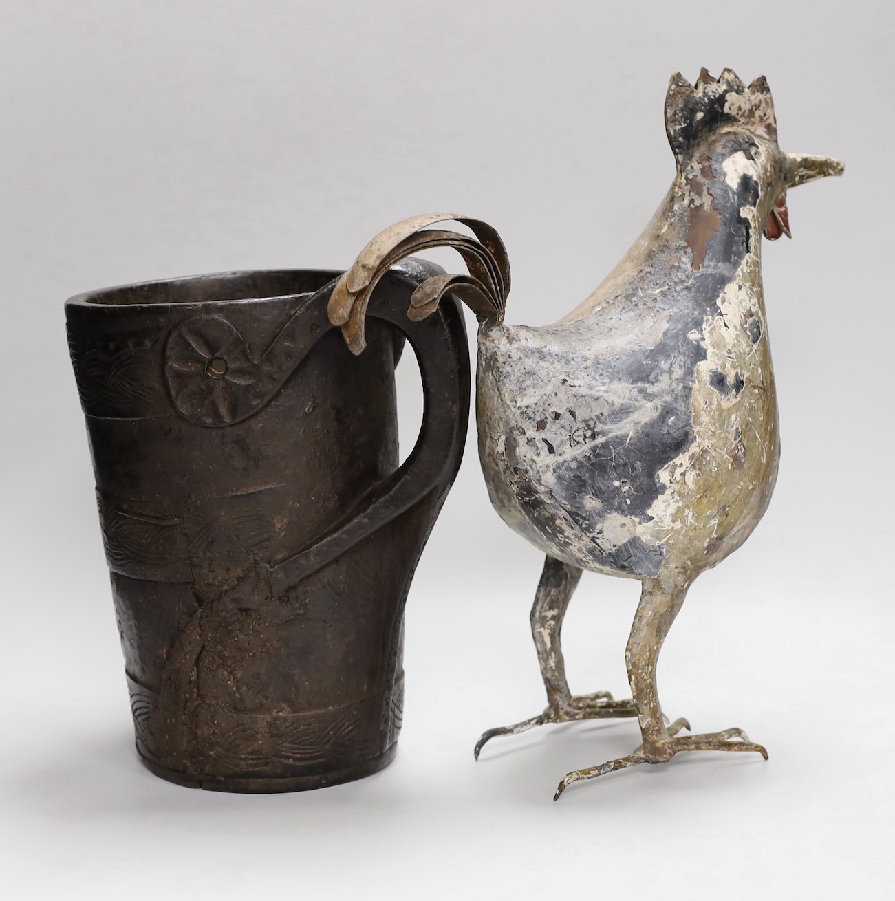 An 18th century Scandinavian carved wood tankard and a 19th century painted tin plated iron model of a cockerel, 36.5cm high.